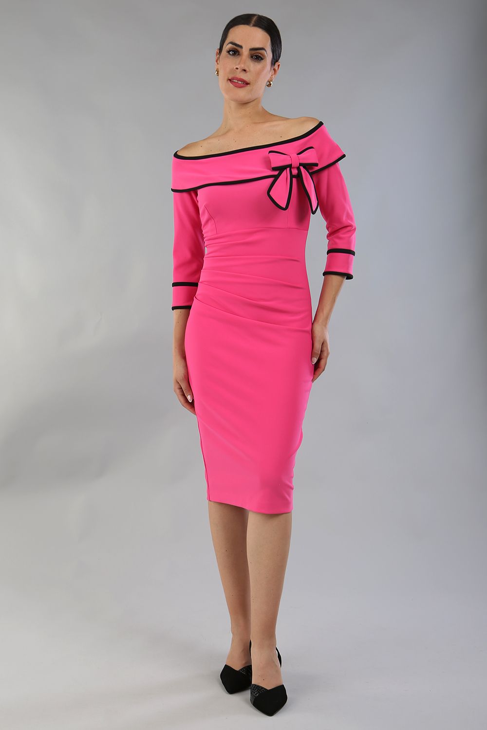 model wearing a diva catwalk Paige Bi-Stretch Dress with 3/4 sleeve, knee length, Fold over off-shoulder neckline with bow detail and with Contrast piping on sleeve cuffs and neckline in Hibiscus Fuchsia and black colour