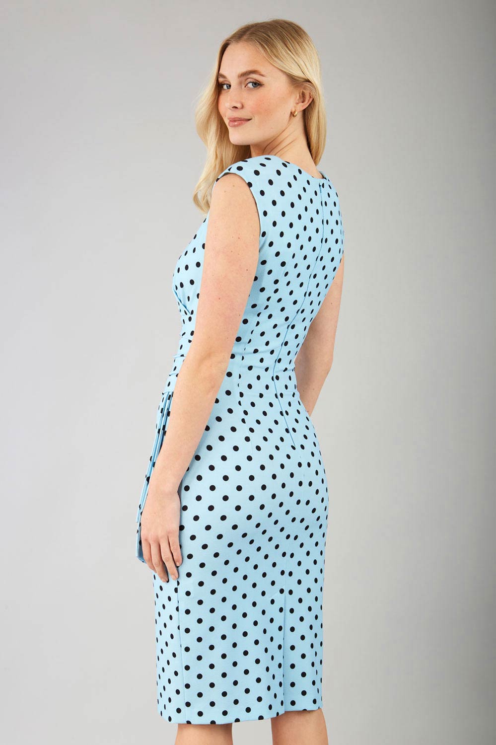 Brunette model wearing Diva Catwalk Perry Polka Dot Pencil Sleeveless Dress with tie detail on a side and rounded neckline in sky blue front