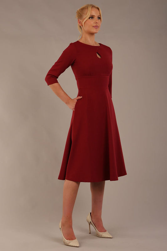 model is wearing diva catwalk casares swing dress with a keyhole neckline three quarter sleeve dress with pocket detail in Wine front side (Wine)
