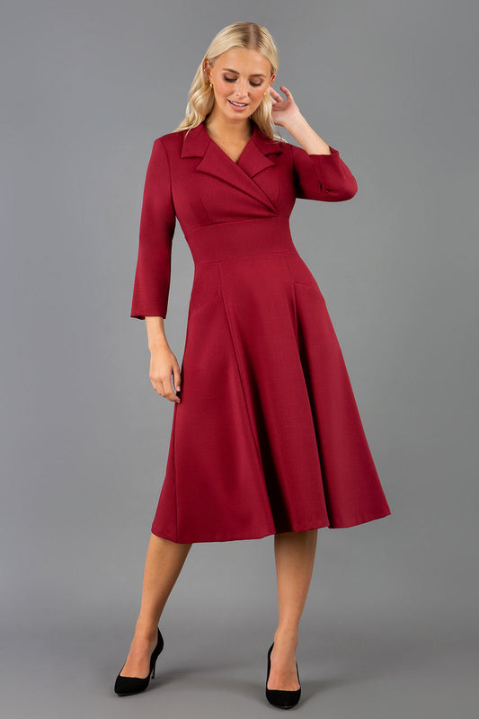 A blonde model is wearing a swing wine three quarter sleeve dress with oversized collar and pockets in the skirt