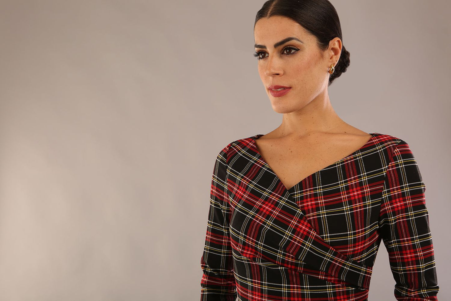 model is wearing a diva catwalk Horizon Tartan Stretch Pencil Dress with crossover v neckline and 3/4 sleeves and pleating details and knee length in luxury tartan stretch fabric in Royal Red Tartan close up