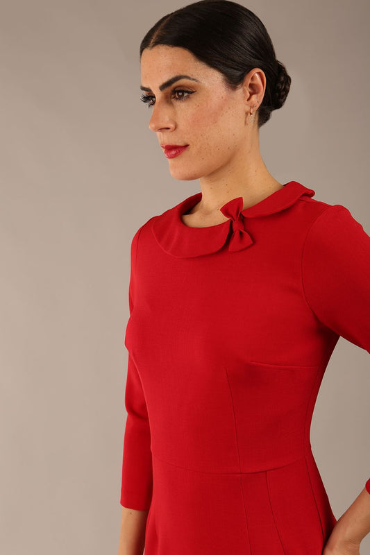 brunette model is wearing a diva catwalk Helium 3/4 Sleeved Pencil Dress with 3/4 sleeve and knee length and bow detail on the neckline in dark red colour front close up