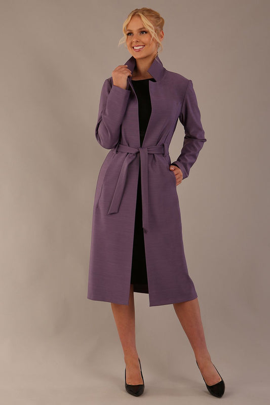 Model wearing a diva catwalk Paloma midi coat worn open over a black dress to show its versatility against a plain background (Dusky Lilac)