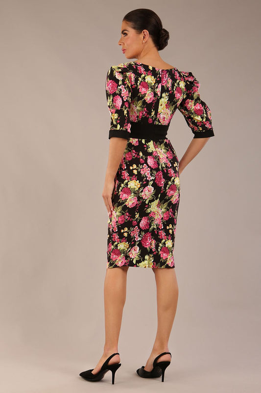 The brunette model is wearing a 7004 diva catwalk Somerset Floral with Puff Sleeves & Black Waistband v neckline and knee length Pencil Dress in Black Spring Flower print back image