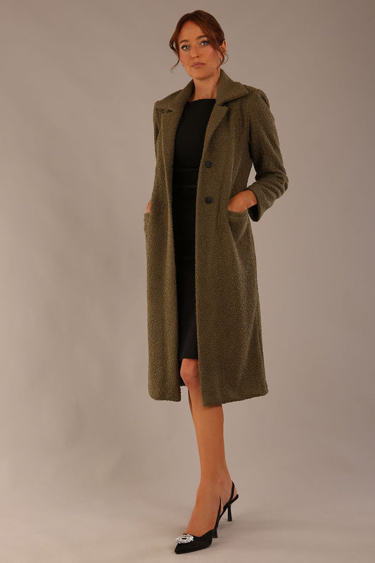 Model wearing the Ambrose boucle midi coat in olive green, long sleeves teddy feeling with a collar neckline and 2 closure buttons at the front and pockets (Olive Green)