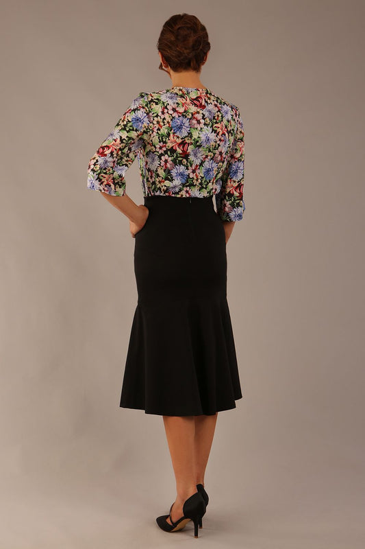 Model wearing a Suki asymmetric draped top in the Aurora Botanical print, styled with a olive green pencil skirt (Aurora Botanical)