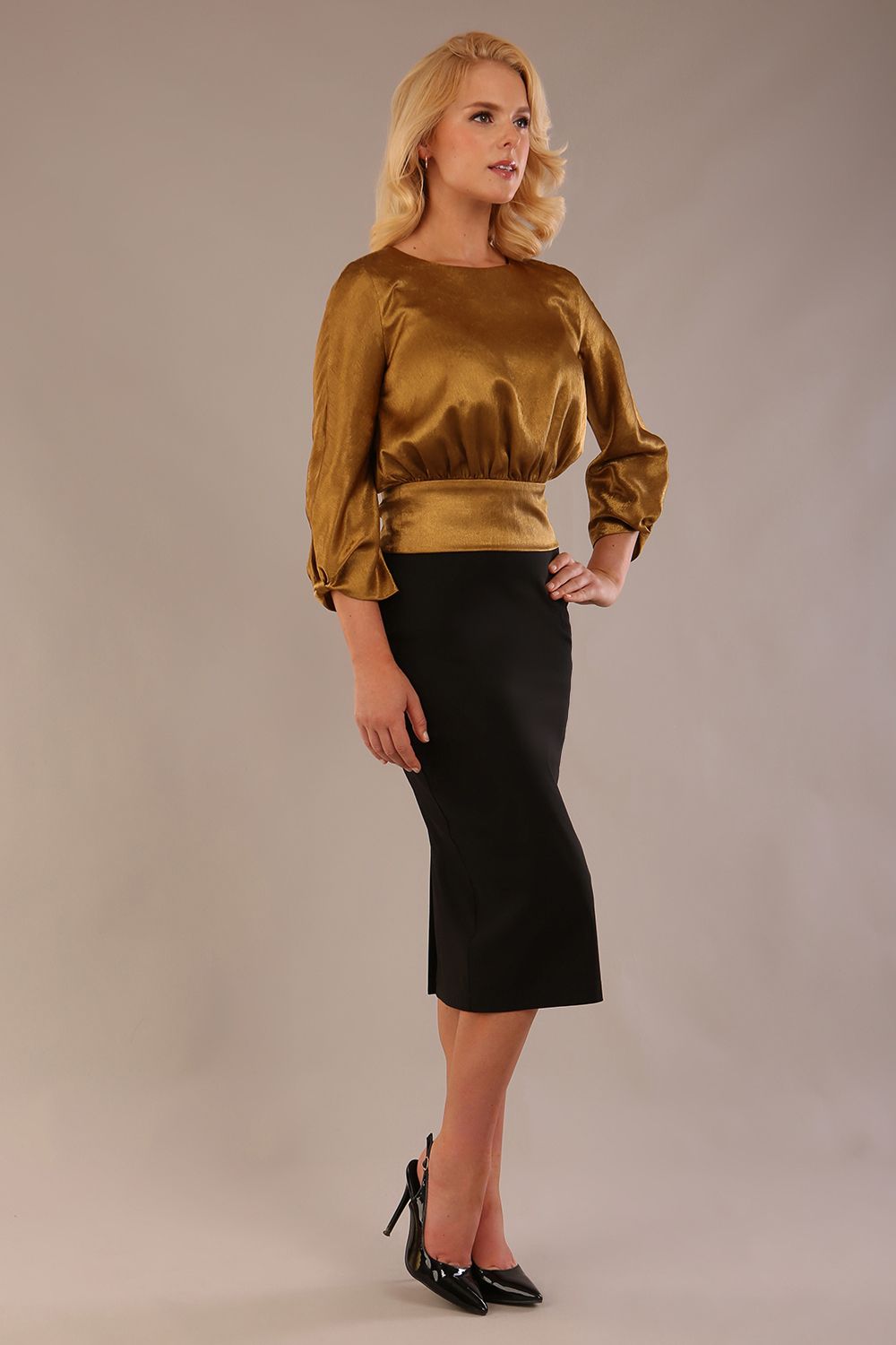 Model wearing a Hollywood lustre gold top with a blouson silhouette and a black pencil skirt close up (Rich Gold)