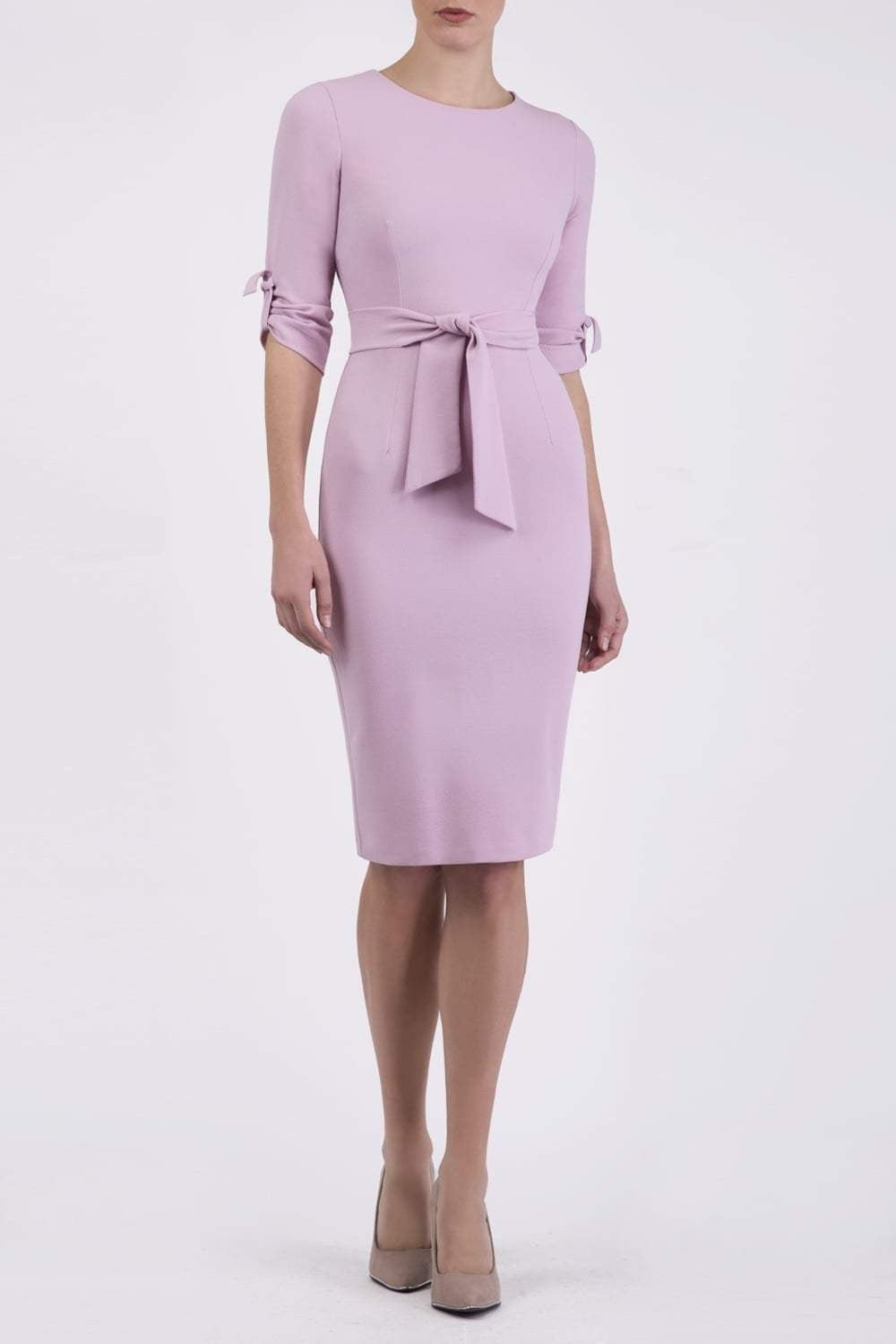 brunette model wearing diva catwalk tryst pencil dawn pink dress with sleeves and belt detail at the front with rounded neckline front