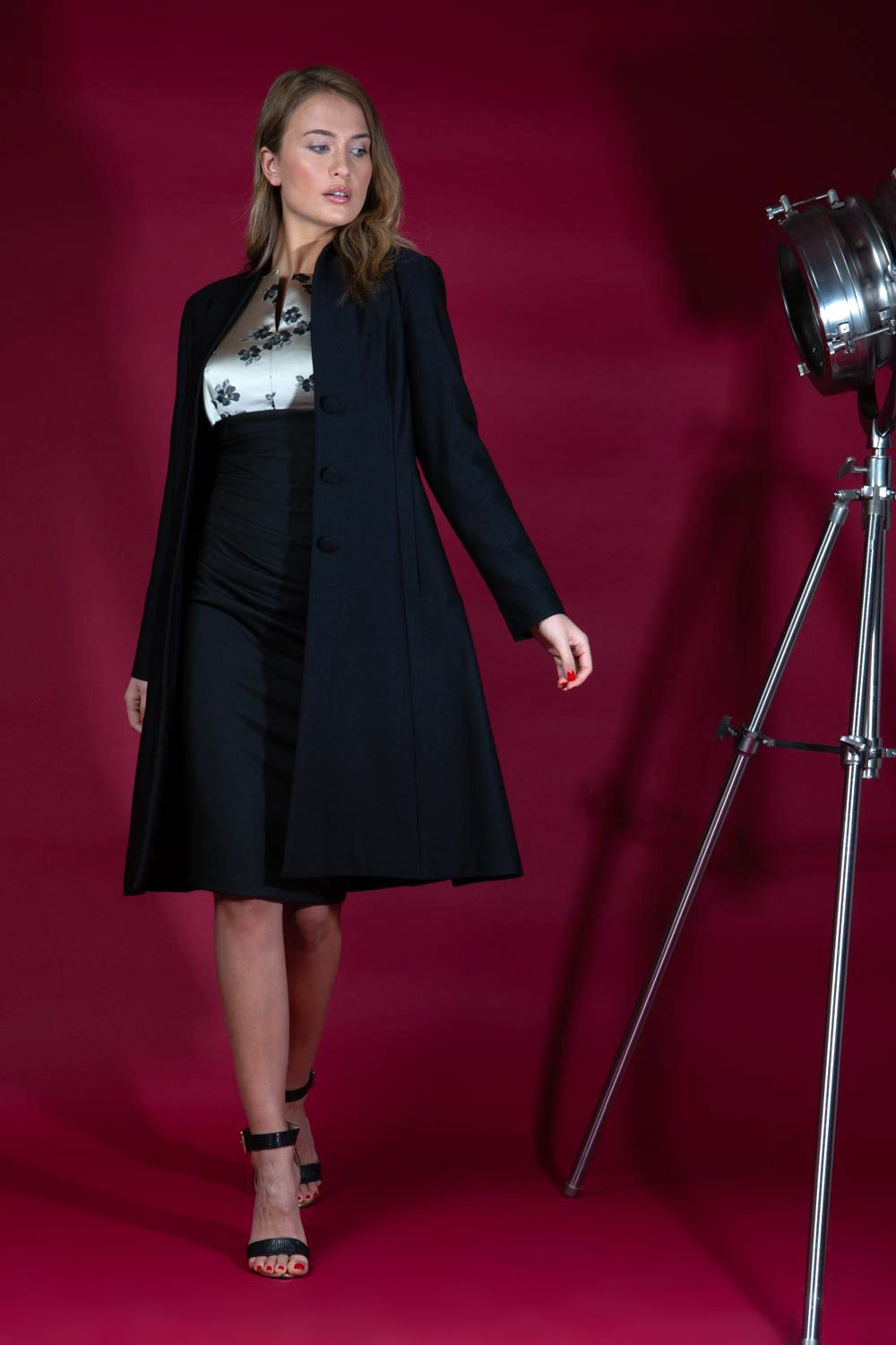 model wearing diva catwalk couture fine raquella coat with buttons across the front and long sleeves with high neck and pockets in black colour front (Black)