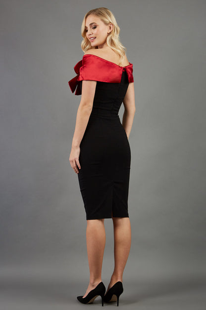 blonde model wearing diva catwalk samantha off shoulder pencil dress with satin red bow detail with a diamante brooch in black front