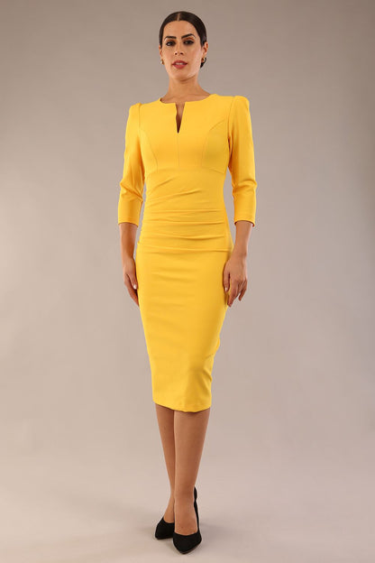 model is wearing a diva catwalk seed fitzrovia 3/4 sleeve pencil dress with round neckline and v-slit and pleating details on the skirt in daffodil yellow front
