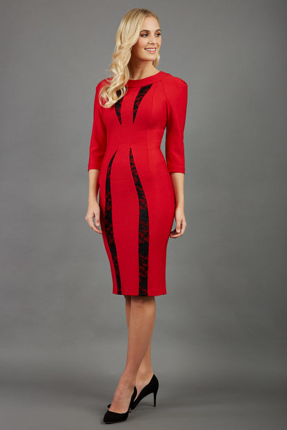 blonde model wearing seed lace red dress with sleeves and rounded necline with lace details pointing towards the band back
