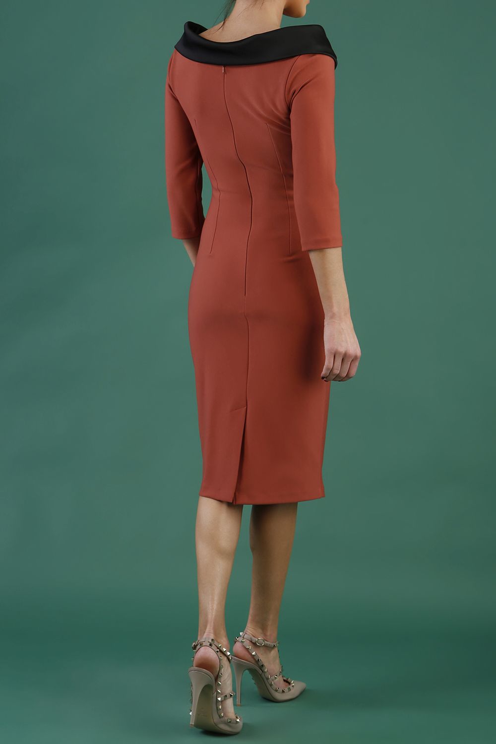 model is wearing diva catwalk pencil dress with contrasting asymmetric satin neckline in marsala brown front with black accents standing in an art gallery.