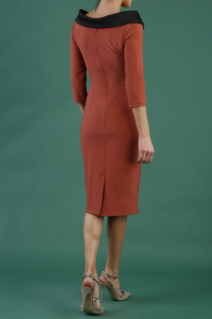 model is wearing diva catwalk pencil dress with contrasting asymmetric satin neckline in marsala brown front with black accents standing in an art gallery.