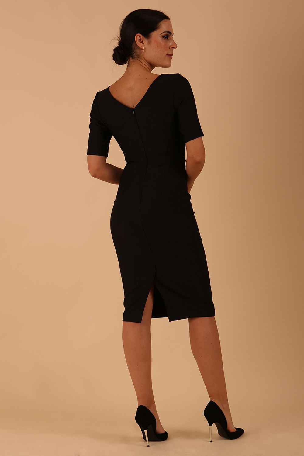 model wearing diva catwalk couture wiltshire fitted pencil-skirt dress with short sleeves and open v-neckline and pleating across the tummy area in black colour front