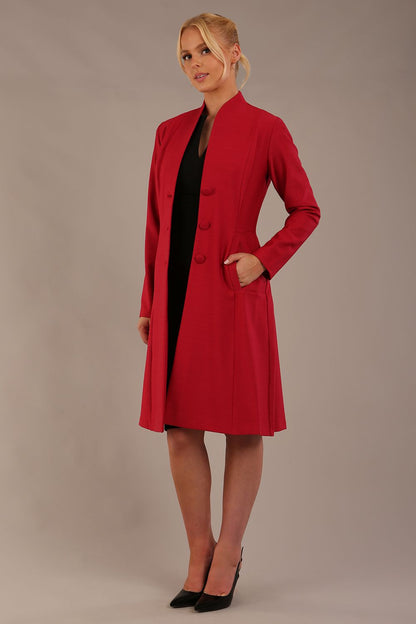 blonde model wearing diva catwalk couture fine raquella coat with buttons across the front and long sleeves with high neck and pockets in crimson pink colour front side (Crimson Pink)