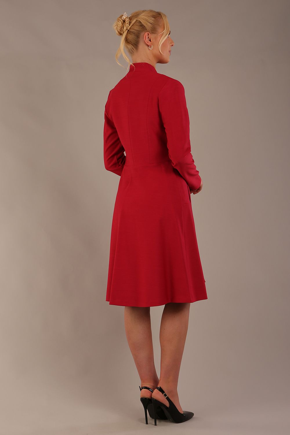 blonde model wearing diva catwalk couture fine raquella coat with buttons across the front and long sleeves with high neck and pockets in crimson pink colour front side (Crimson Pink)