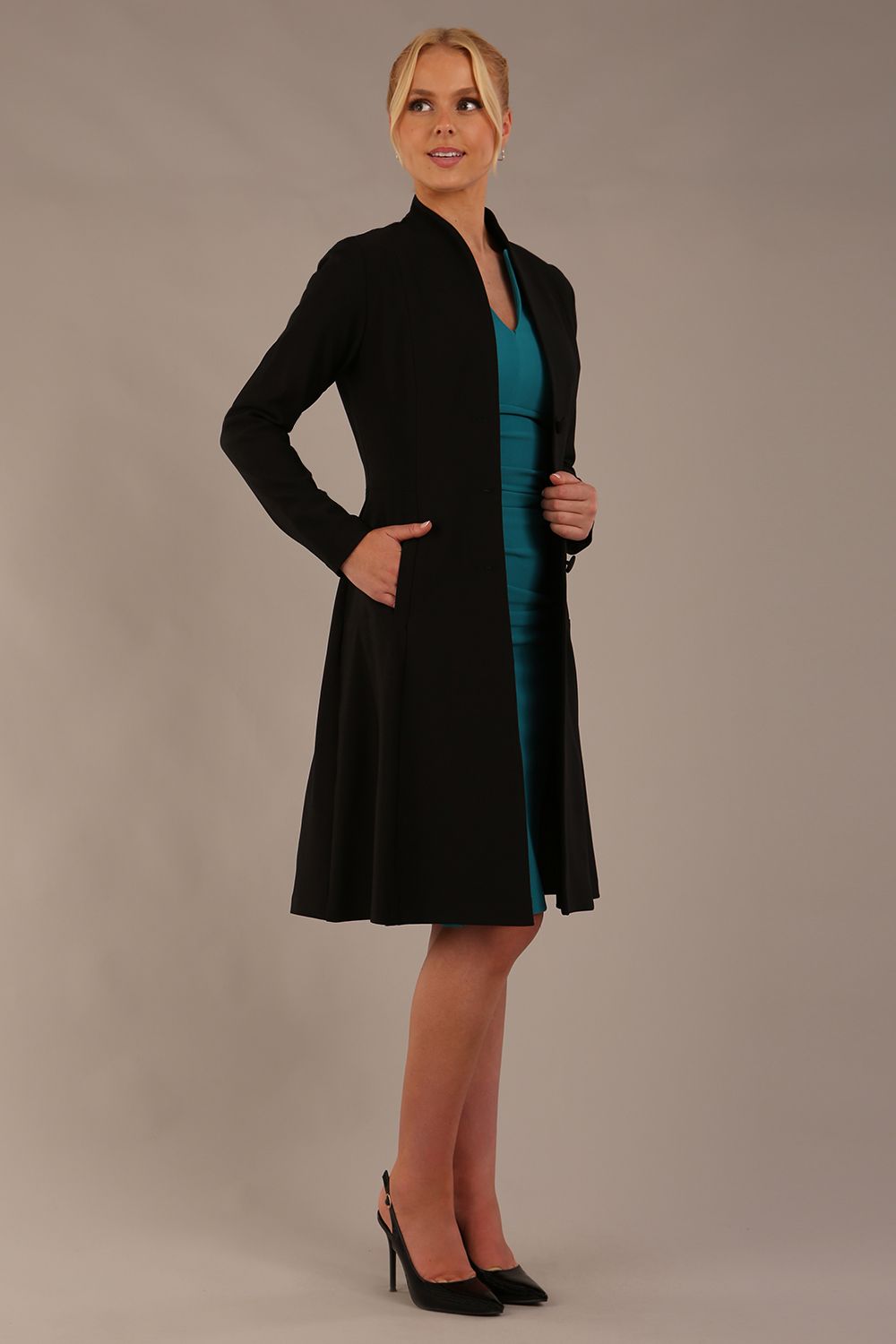 model wearing diva catwalk couture fine raquella coat with buttons across the front and long sleeves with high neck and pockets in black colour front (Black)