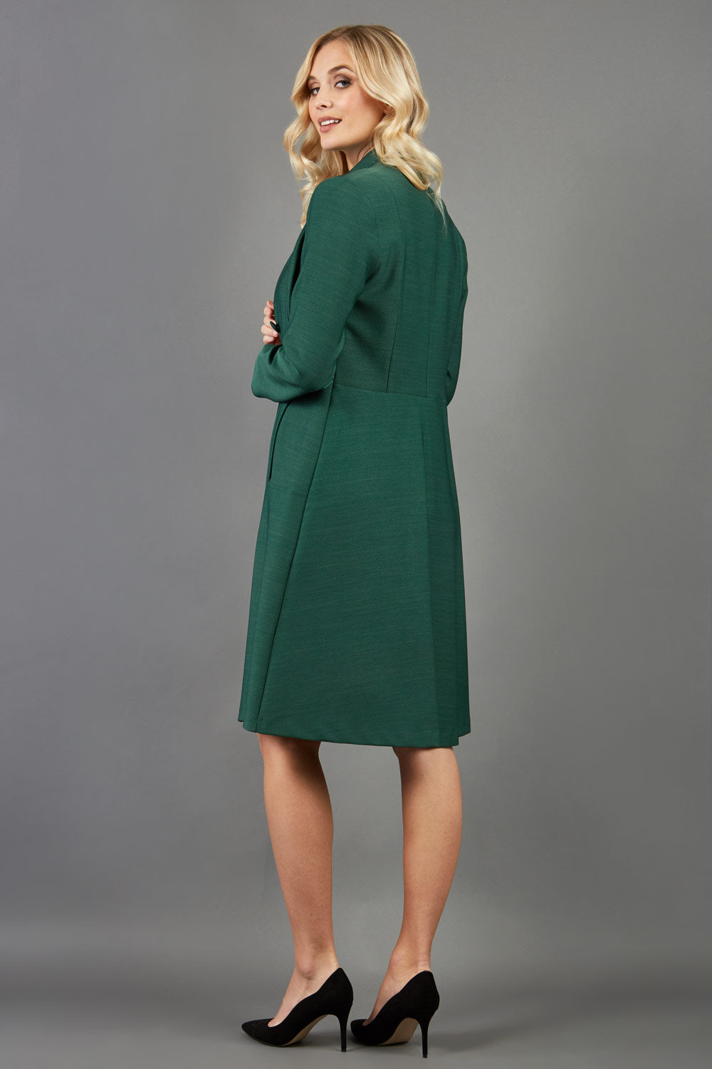 blonde model wearing diva catwalk couture fine raquella coat with buttons across the front and long sleeves with high neck and pockets in chrome green colour front (Chrome Green)