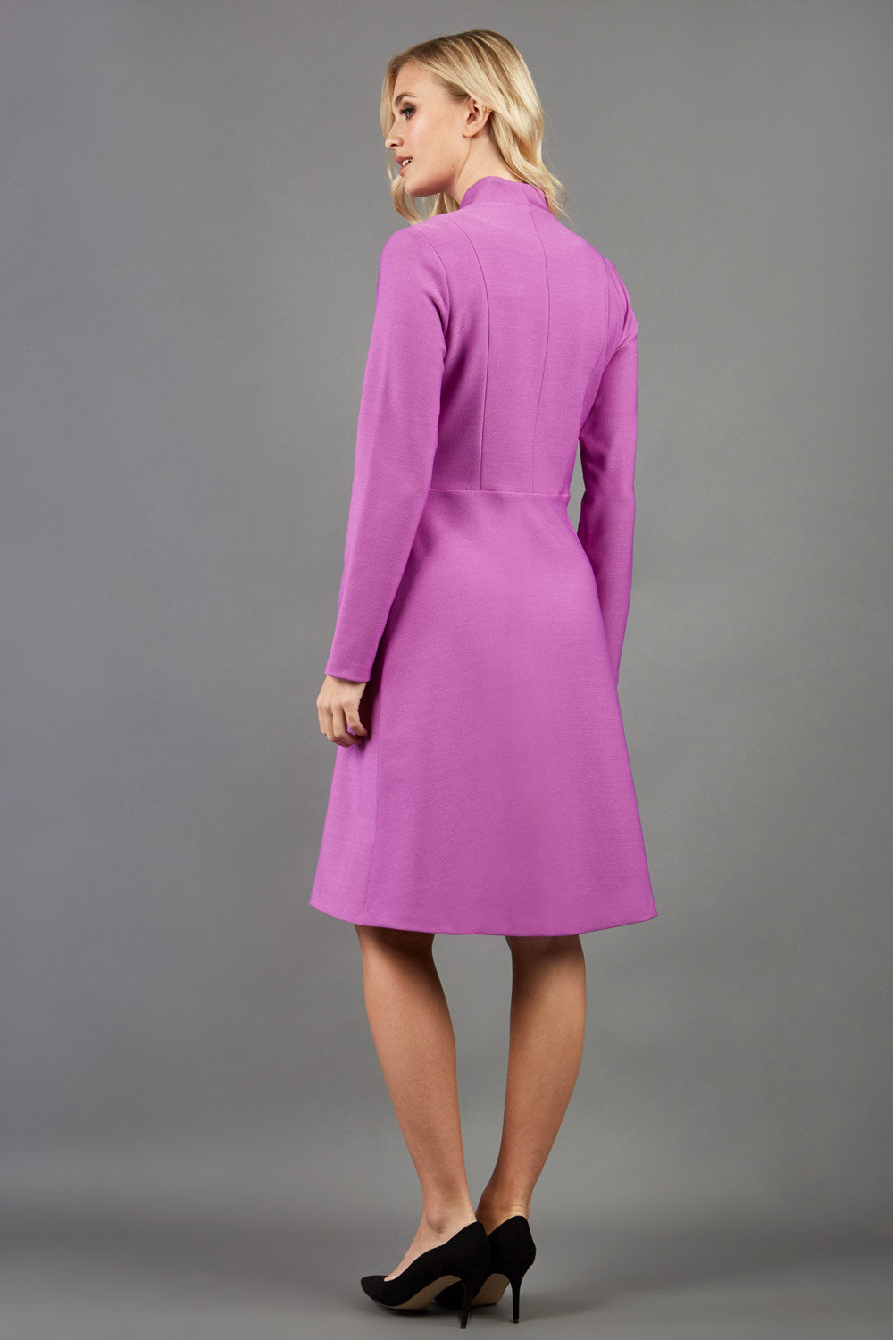 blonde model wearing diva catwalk couture fine raquella coat with buttons across the front and long sleeves with high neck and pockets in magenta mist colour front (Magenta Mist)
