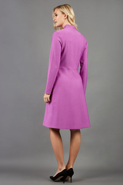 blonde model wearing diva catwalk couture fine raquella coat with buttons across the front and long sleeves with high neck and pockets in magenta mist colour front (Magenta Mist)
