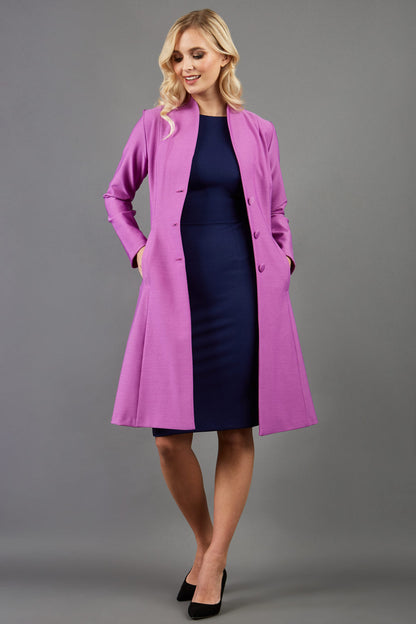 blonde model wearing diva catwalk couture fine raquella coat with buttons across the front and long sleeves with high neck and pockets in magenta mist colour front (Magenta Mist)