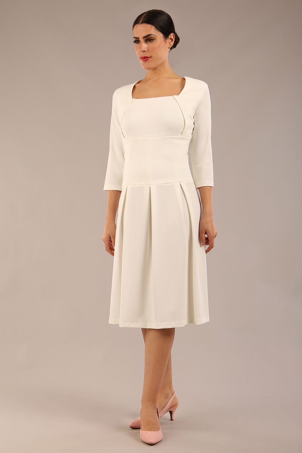 brunette model wearing a diva catwalk malinda swing dress with 3/4 sleeves and knee length and wide waistband in ripple crepe fabric in ivory cream colour front image