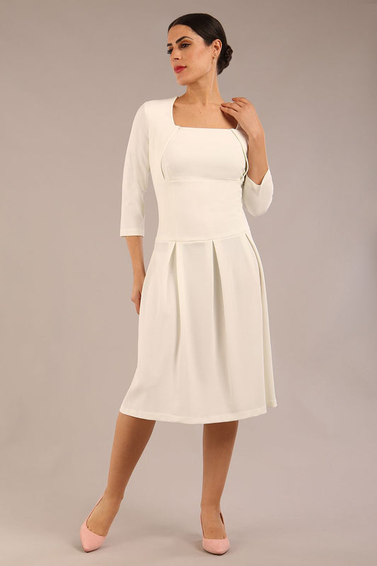 brunette model wearing a diva catwalk malinda swing dress with 3/4 sleeves and knee length and wide waistband in ripple crepe fabric in ivory cream colour front image