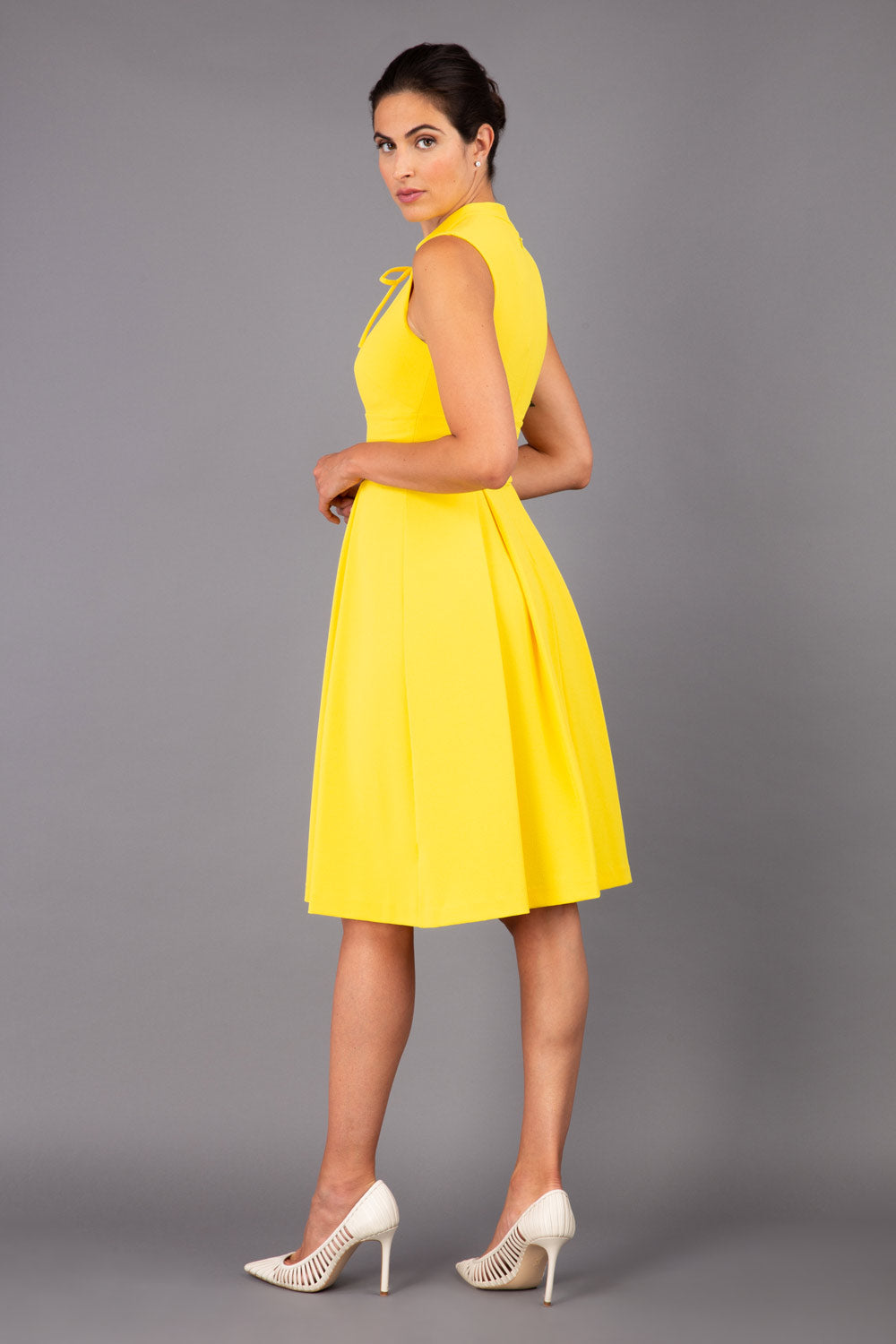 brunette model wearing diva catwalk oceana a-line swing skirt sleeveless dress with funnel neckline and tie detail in yellow front