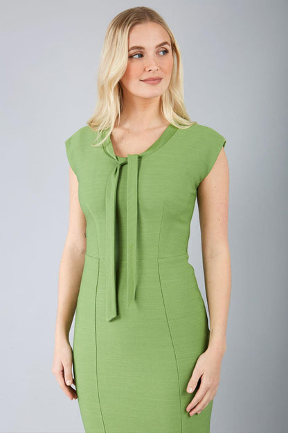 blond model wearing a diva catwalk seed lucca tie detail cap sleeves pencil dress in citrus green colour front image