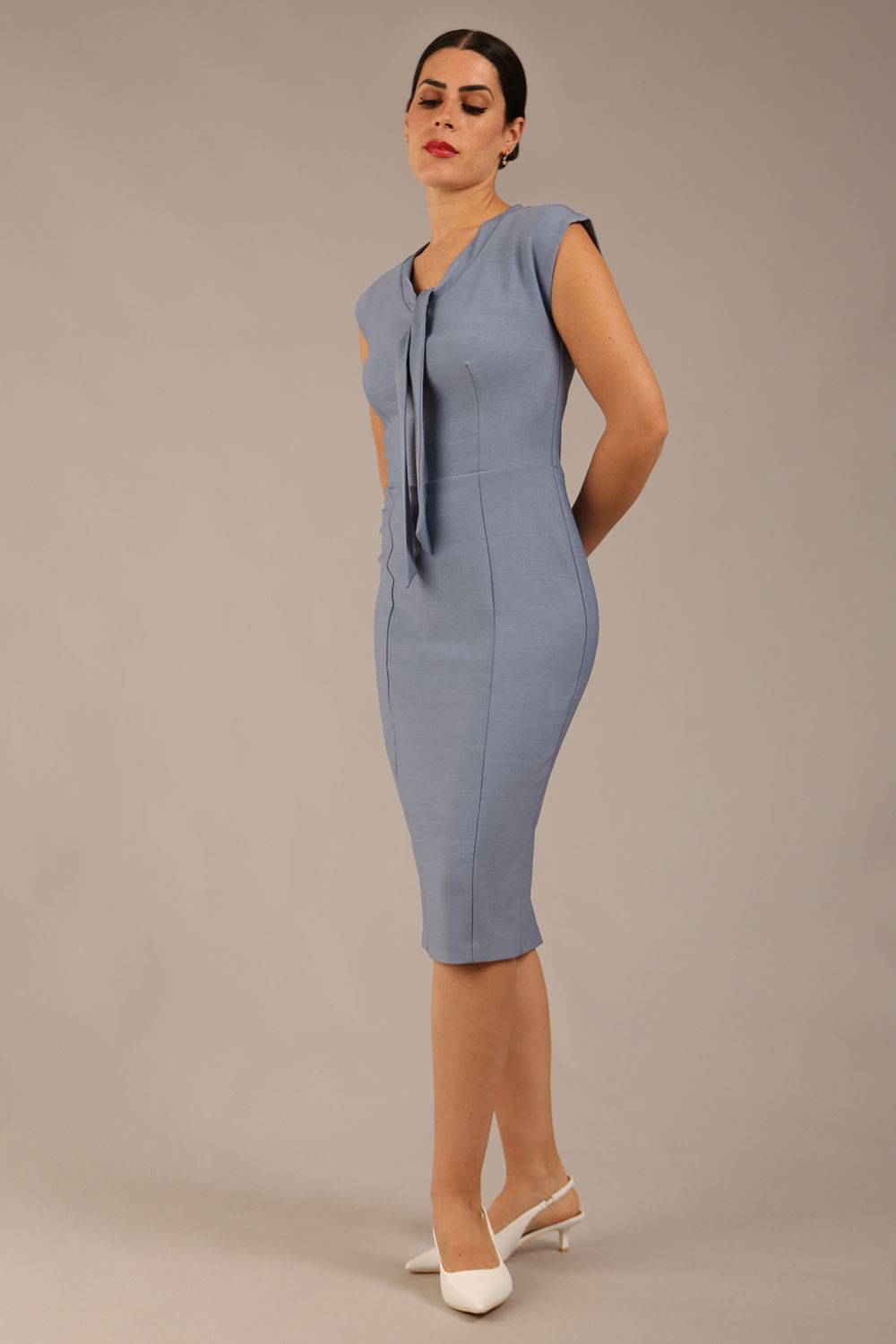 brunette model wearing a diva catwalk seed lucca tie detail cap sleeves pencil dress in steel blue colour front side image