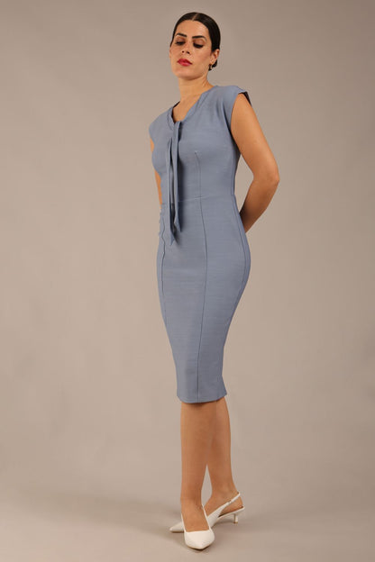 brunette model wearing a diva catwalk seed lucca tie detail cap sleeves pencil dress in steel blue colour front side image