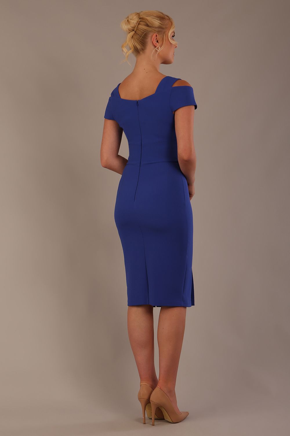 Woman wearing a riviera blue diva catwalk hayward pencil dress with short sleeves against a beige background back view