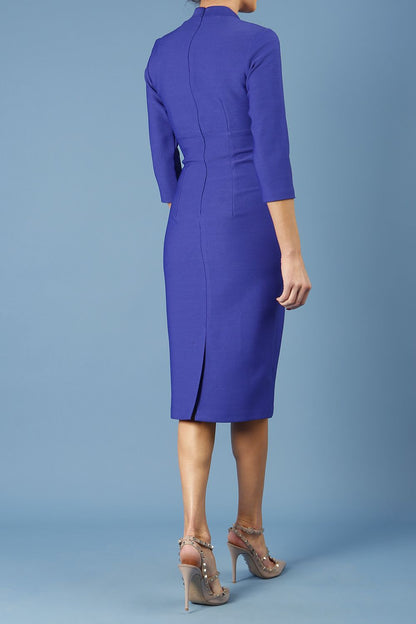 model is wearing diva catwalk seed holsworthy pencil dress with pleating on a tummy area and high neck with sleeves in palace blue front