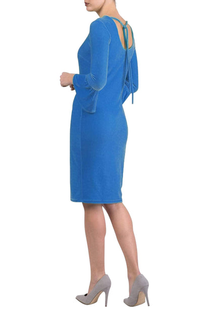 A brunette model is wearing a velvet long bell sleeve pencil dress maternity style in blue jewel colour back