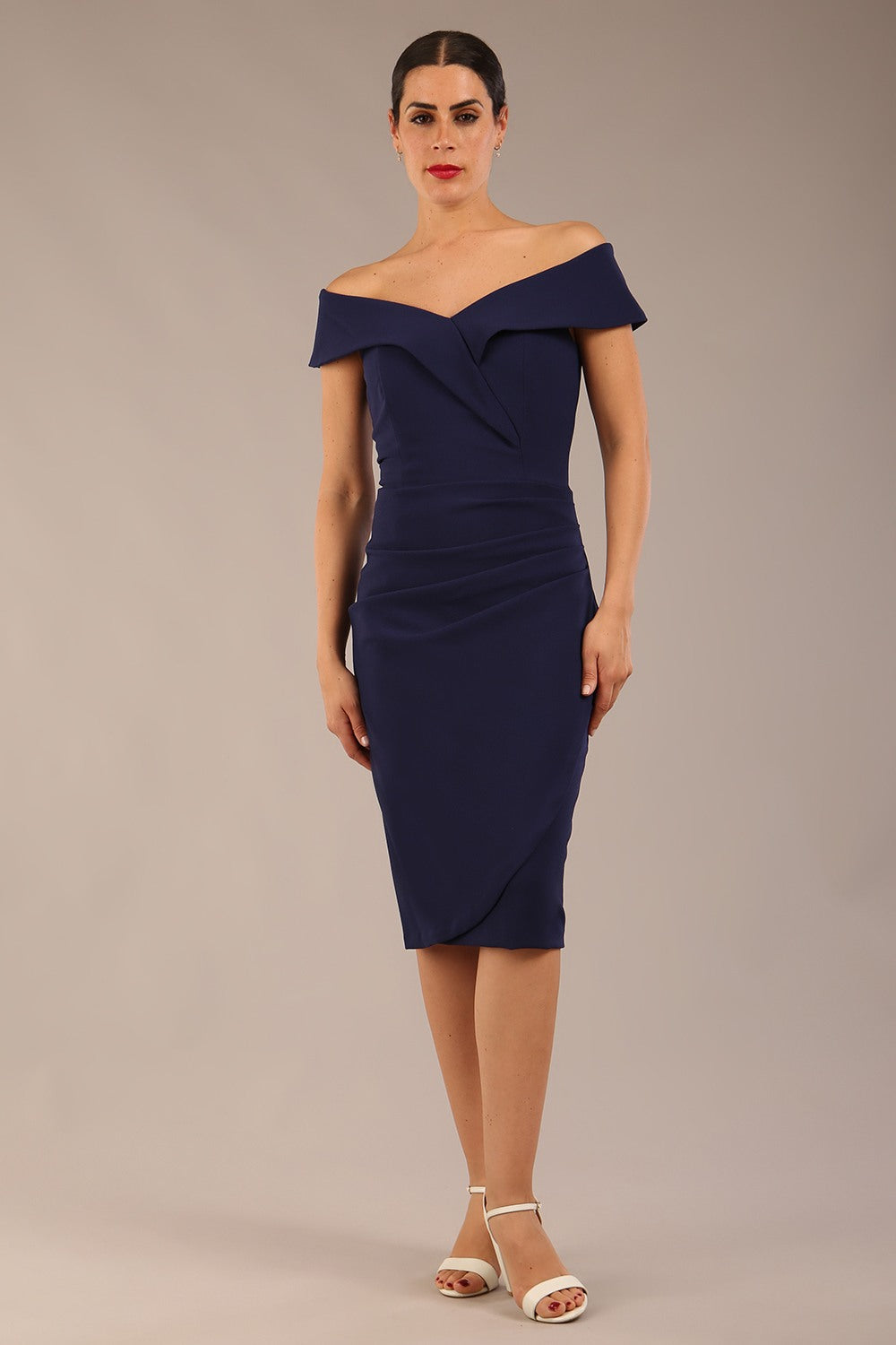 brunette model wearing diva catwalk pencil skirt dress sleeveless with lowered neckline and pleating on side in navy blue colour front image