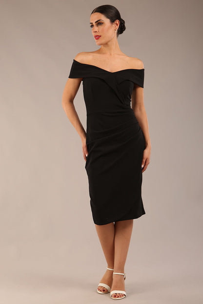 brunette model wearing diva catwalk pencil skirt dress sleeveless with lowered neckline and pleating on side in black colour front image
