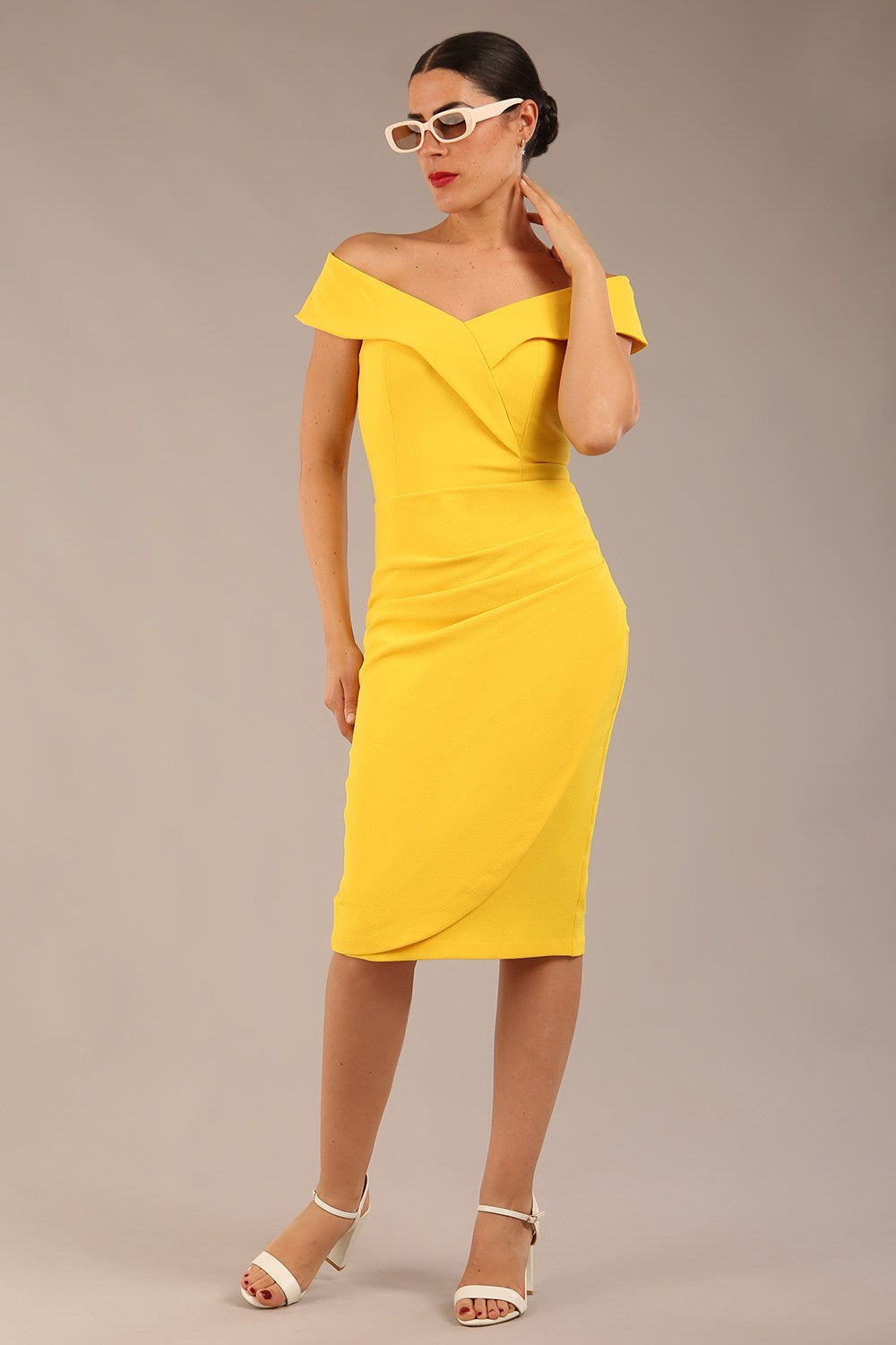 brunette model wearing diva catwalk pencil skirt dress sleeveless with lowered neckline and pleating on side in freesia yellow colour front image with sun glasses