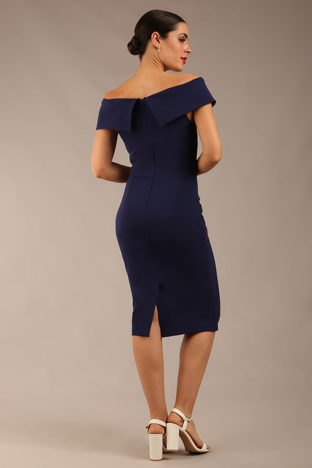 brunette model wearing diva catwalk pencil skirt dress sleeveless with lowered neckline and pleating on side in navy blue colour front image