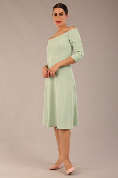brunette model is wearing diva catwalk off shoulder swing a-line islay dress with sleeves in deco green colour front image 