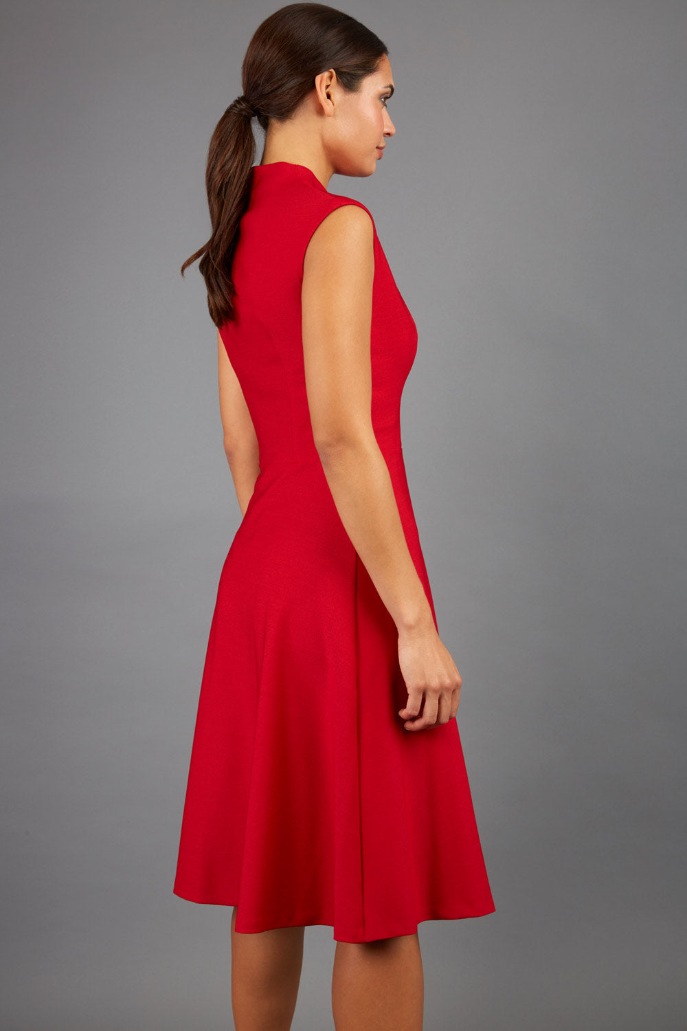 Brunette Model is wearing a sleeveless swing high neck dress with high neck in cardinal red by Diva Catwalk front