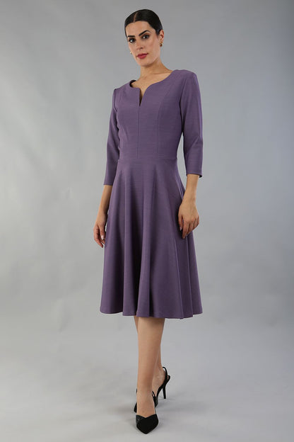 model wearing a diva catwalk Seed Corsham Swing Dress with 3/4 sleeve and below the knee length with v slit detail on the neckline in dusky lilac colour