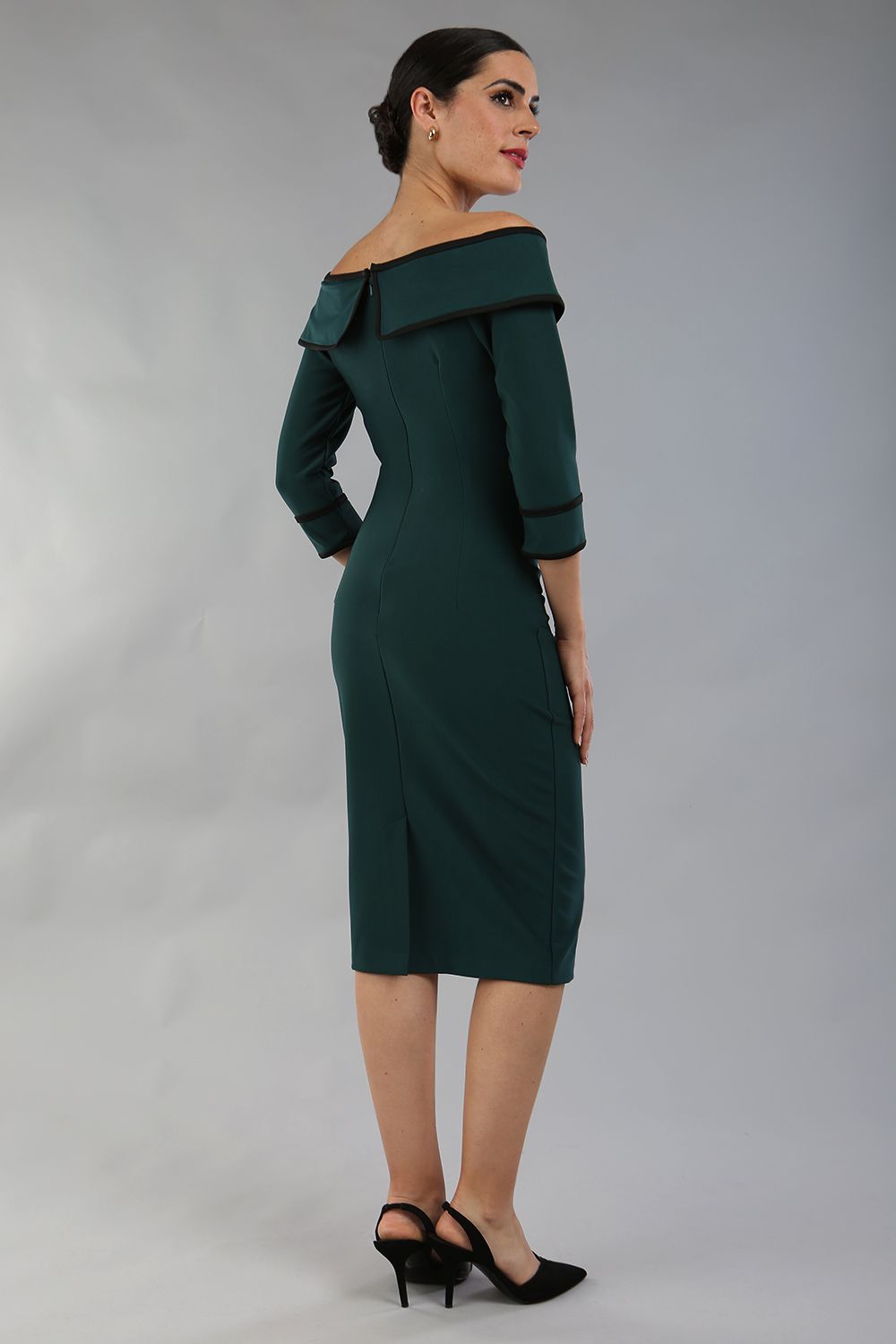 model wearing a diva catwalk Paige Bi-Stretch Dress with 3/4 sleeve, knee length, Fold over off-shoulder neckline with bow detail and with Contrast piping on sleeve cuffs and neckline in Forest Green and black colour