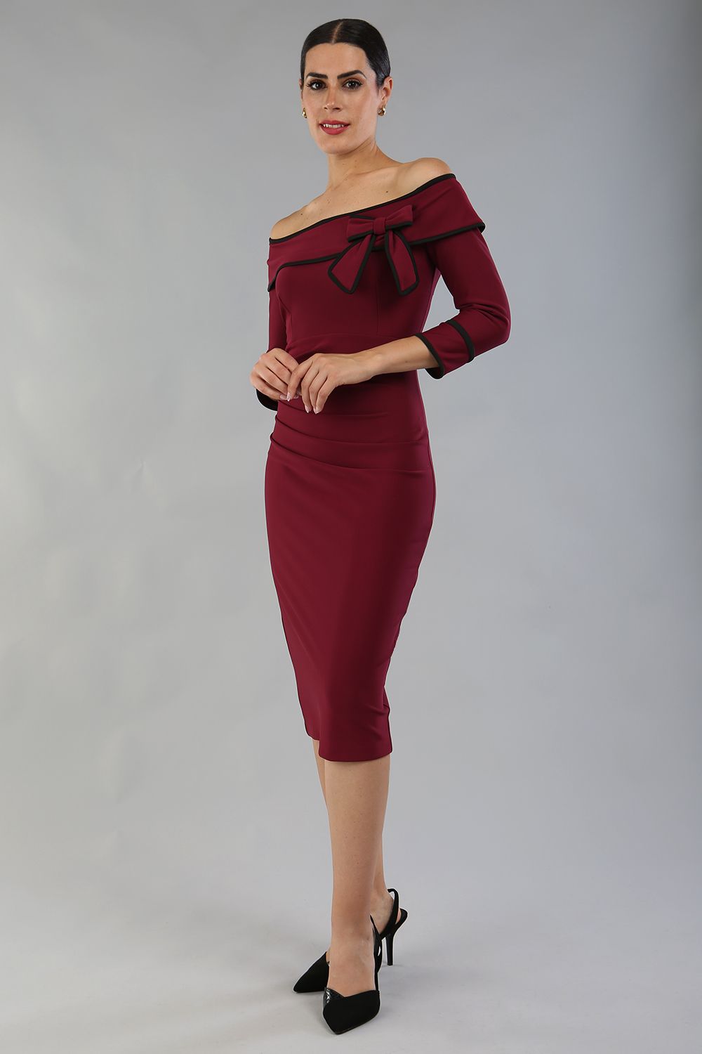 model wearing a diva catwalk Paige Bi-Stretch Dress with 3/4 sleeve, knee length, Fold over off-shoulder neckline with bow detail and with Contrast piping on sleeve cuffs and neckline in Burgundy and black colour