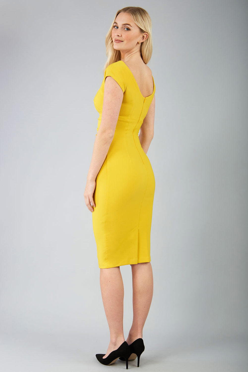 Model wearing Diva Catwalk Polly Rounded Neckline Pencil Cap Sleeve Dress with pleating across the tummy area in Mustard Yellow front side