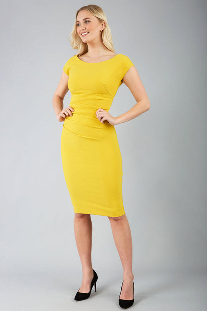 Model wearing Diva Catwalk Polly Rounded Neckline Pencil Cap Sleeve Dress with pleating across the tummy area in Mustard Yellow front side