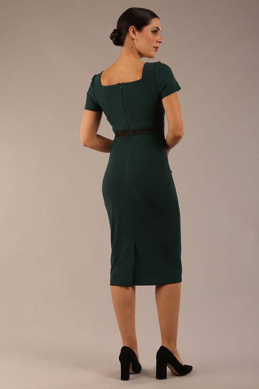 model is wearing a diva catwalk dress in forest green with black satin detail contrast on the neckline and waistband short sleeves and pleating details with knee-length back