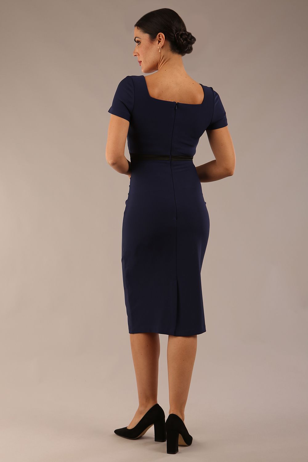 model is wearing a diva catwalk dress in navy blue with black satin detail contrast on the neckline and waistband short sleeves and pleating details with knee-length back
