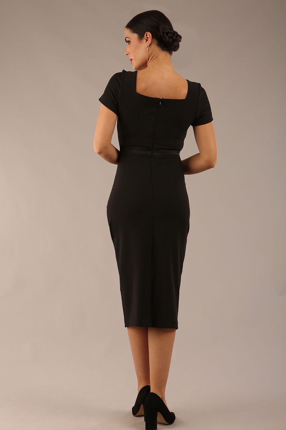 model is wearing a diva catwalk dress in black with black satin detail contrast on the neckline and waistband short sleeves and pleating details with knee length back