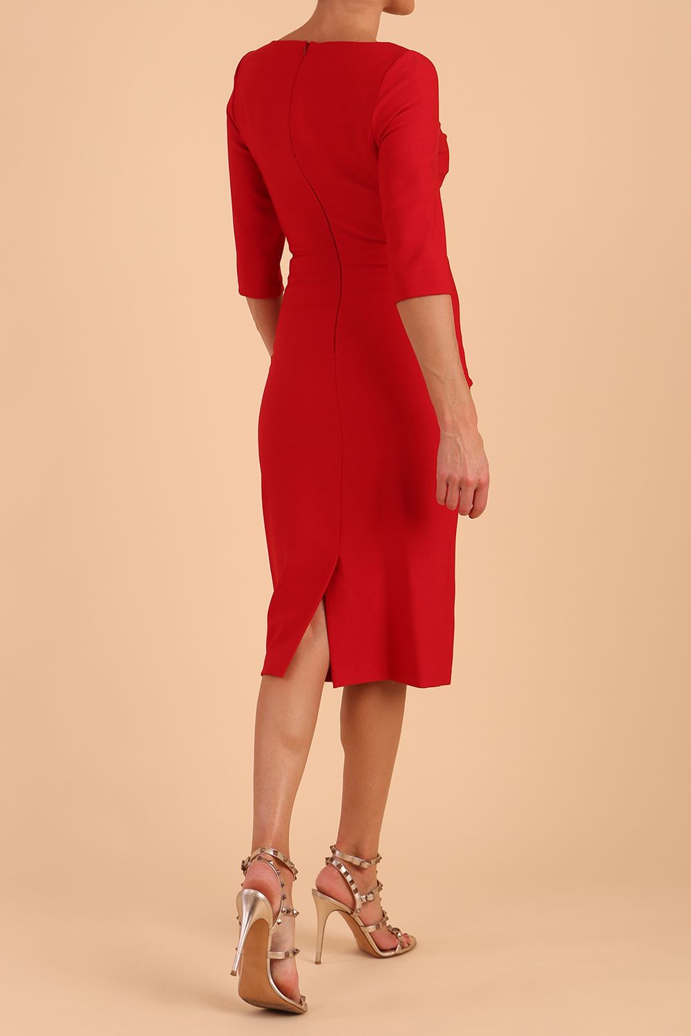 model wearing seed couture royale pencil skirt dress with pleating across the tummy area with rounded neckline with a split in the middle and 3 4 sleeve in Salsa Red colour front side